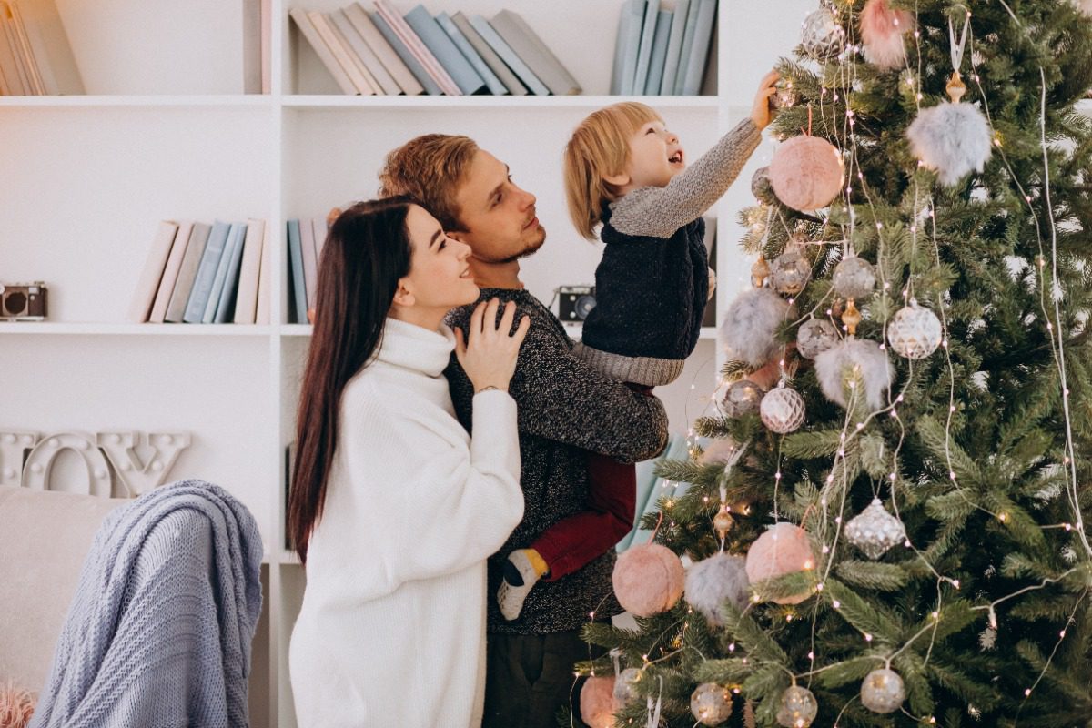 young-family-decorating-a-christmas-tree-with-toddler-son A young couple decorates a Christmas tree with their toddler